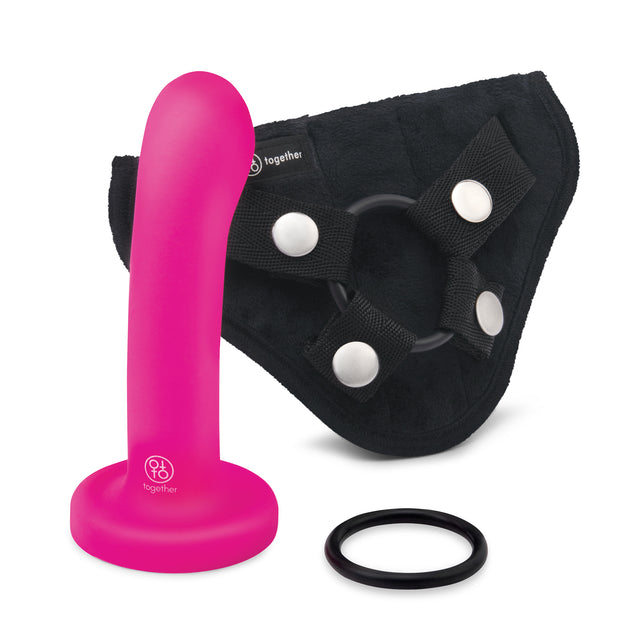 A pink silicone dildo with a smooth texture is shown alongside an adjustable black silicone harness with a stable base and additional ring.