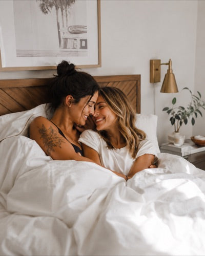 Couple laughing together in bed on a sunlit morning