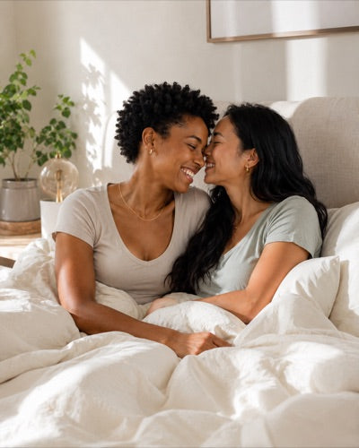Two partners sharing a smile in bed in soft morning light
